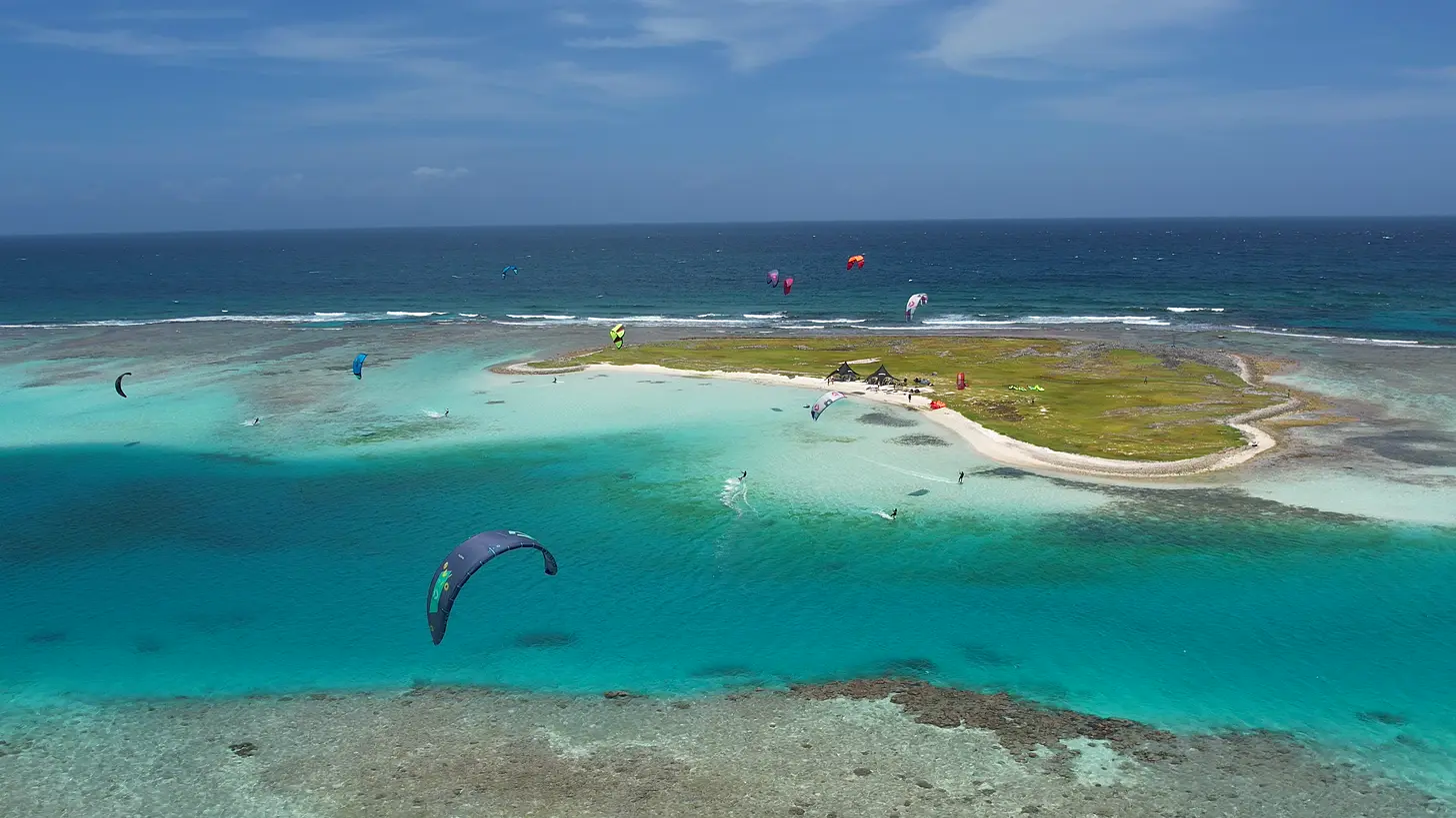 Vista aérea do arquipélago de Los Roques, na Venezuela, com lagoa de água verde-turquesa, banco de areia e kitesurfistas velejando