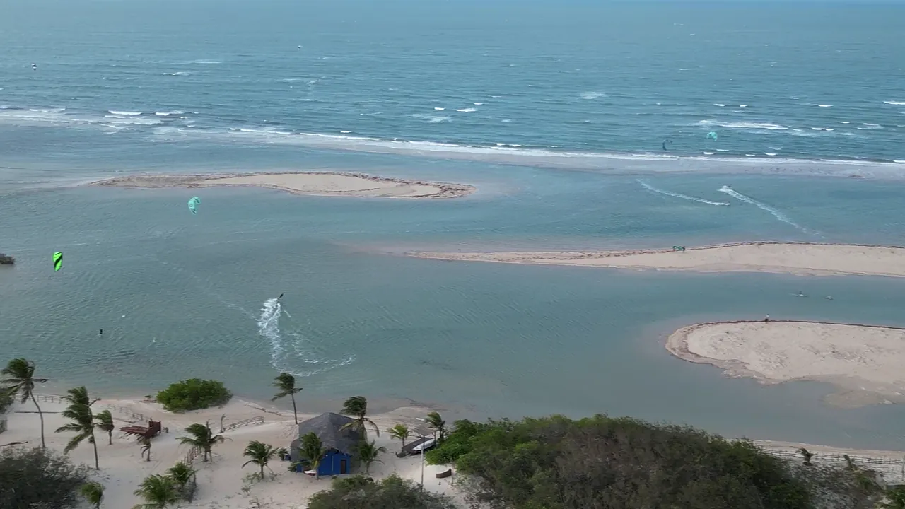 Lagoa de água plana em Tatajuba, no Ceará, com um kite verde velejando ao lado dos bancos de areia, cenário ideal para iniciantes
